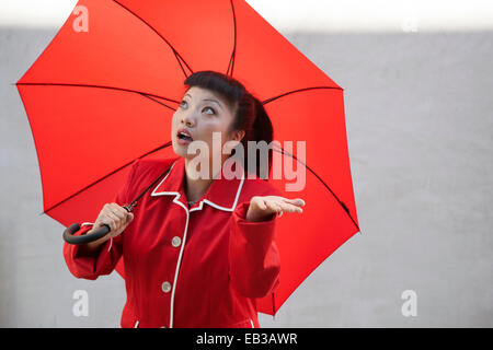 Frau mit Regenschirm im Regenmantel Stockfoto