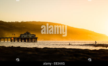 Silhouette von Surfern und Pier bei Sonnenaufgang, Malibu, Kalifornien, USA Stockfoto