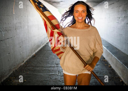 Kaukasische Frau, die die amerikanische Flagge im tunnel Stockfoto