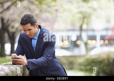 Mann im Anzug mit Handy im Stadtpark Stockfoto