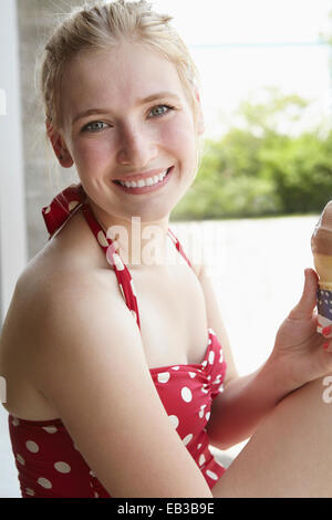 Lächelnde Frau in Badeanzug essen Eiscreme-Kegel Stockfoto