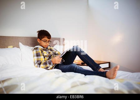 Gemischte Rassen Junge liest Magazin im Schlafzimmer Stockfoto