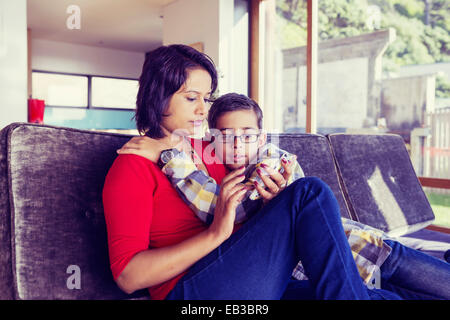 Mutter und Sohn mit Handy im Wohnzimmer Stockfoto