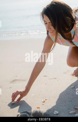 Kaukasische Frau sammelt Muscheln am Strand Stockfoto