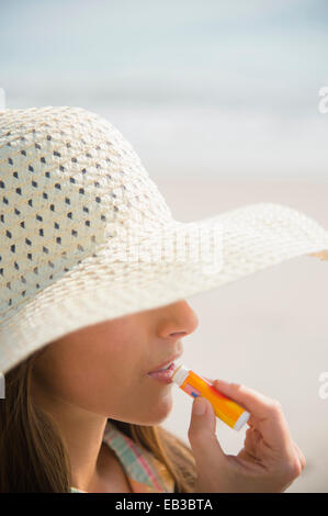 Kaukasische Frau Anwendung von Sonnenschutzmitteln Lippenbalsam am Strand Stockfoto