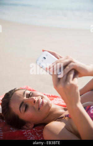 Kaukasische Frau mit Handy am Strand Stockfoto