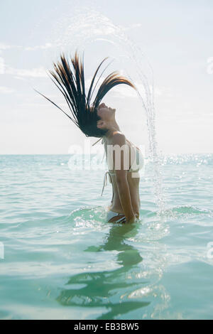 Kaukasische Frau spritzt Haar im Ozean Stockfoto