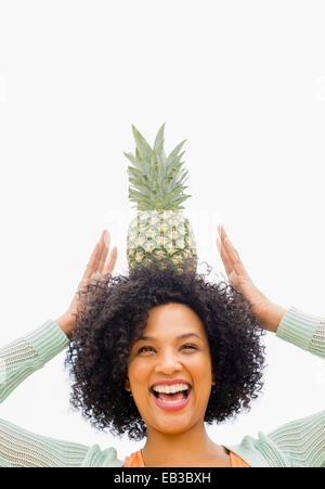 Lächelnde Frau balancieren Ananas am Kopf Stockfoto