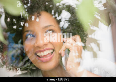 Lächelnde Frau am Handy in der Nähe von Fenster Stockfoto