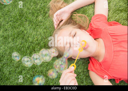Kaukasische Mädchen bläst Seifenblasen auf Rasenfläche Stockfoto