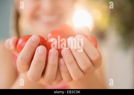 Nahaufnahme von Kaukasischen Mädchen halten Handvoll Tomaten Stockfoto