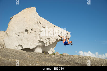 Seitenansicht einer Frau, die einen großen Felsen klettert, Korsika, Frankreich Stockfoto