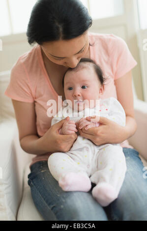 Asiatische Mutter halten Baby im Sessel Stockfoto