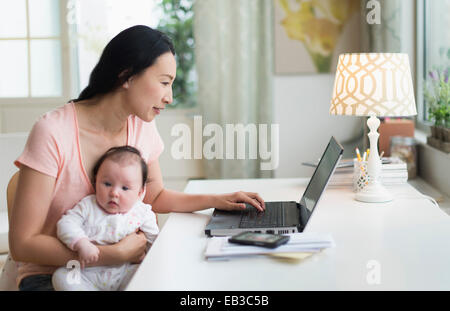 Asiatische Mutter mit Baby von zu Hause aus arbeiten Stockfoto