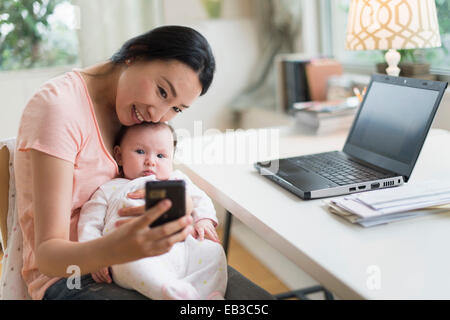 Asiatische Mutter und Baby nehmen Selfie im home-office Stockfoto