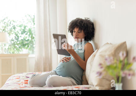 Schwanger African American Mutter mit digital-Tablette im Bett Stockfoto