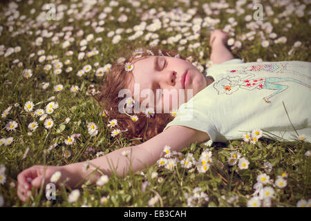 Mädchen liegend in einem Feld von Blumen-Gänseblümchen Stockfoto