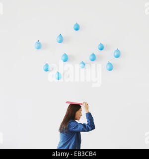 Frau stehend unter konzeptionellen Regentropfen Stockfoto