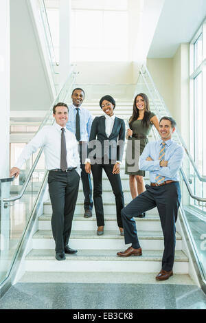 Geschäftsleute, die lächelnd auf Büro-Treppe Stockfoto