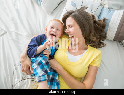 Kaukasische Mutter und Sohn spielen auf Bett Stockfoto