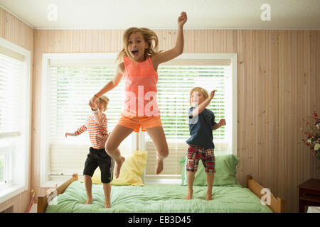 Kaukasische Kinder springen auf Bett Stockfoto