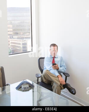 Kaukasische Geschäftsmann mit Handy am Schreibtisch im Büro Stockfoto