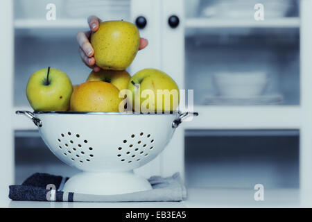 Menschliche Hand, die einen Apfel vom Sieb in Küche Stockfoto