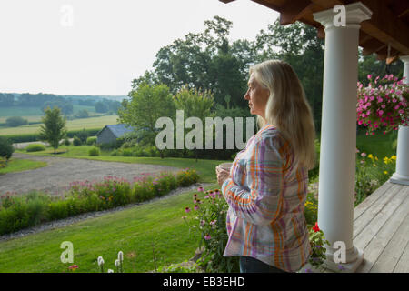 Ältere Frau kaukasischen mit Blick auf ländliche Szene von Veranda Stockfoto