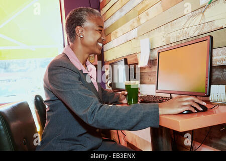 Schwarzen Geschäftsfrau Saft zu trinken, im Internet-café Stockfoto