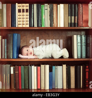 Baby liegend auf Bücherregal im Bücherregal Stockfoto