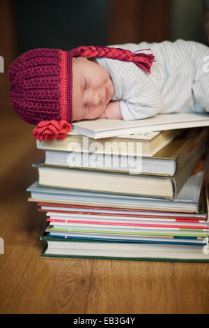 Baby schläft auf Stapel von Büchern Stockfoto