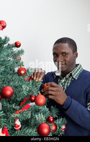 Man den Weihnachtsbaum schmücken und Blick in die Kamera Stockfoto