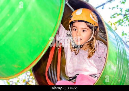 Kleines Mädchen geht durch die Fässer im Abenteuerpark Stockfoto