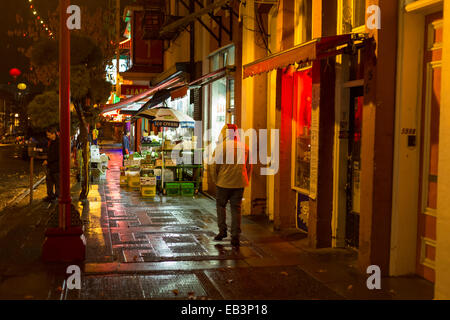 Mann mit Kapuze Jacke, Wandern in Chinatown auf regnerischen Nacht-Victoria, British Columbia, Kanada. Stockfoto