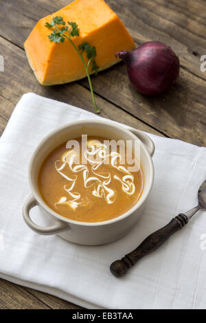 Schüssel mit heißen Kürbissuppe mit Sahne auf Holztisch Stockfoto