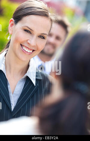 Porträt einer schönen lächelnden jungen Geschäftsfrau oder Geschäftsfrau mit Kollegen im Team-Meeting außerhalb Stockfoto