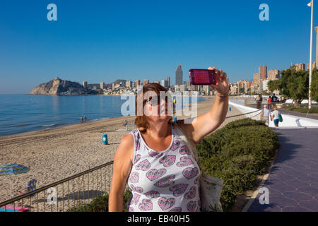 Benidorm, Costa Blanca, Spanien, Europa. Frau touristische Promenade, mit Handy, Handy Selfie selfy übernehmen. Stockfoto