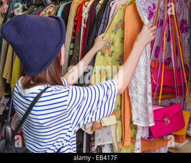 Chinesische Frau, die durch Handtaschen auf Gestellen auf einem Straßenmarkt in Taipeh Stockfoto