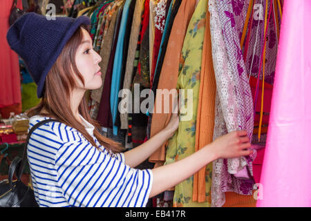 Chinesische Frau, die durch Handtaschen auf Gestellen auf einem Straßenmarkt in Taipeh Stockfoto