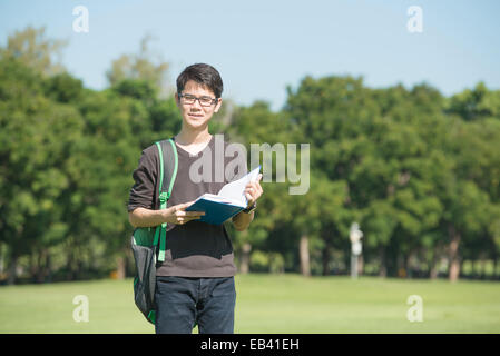 Hübscher Junge hält ein geöffnetes Buch lesen Hintergrund grün Sommerpark Stockfoto