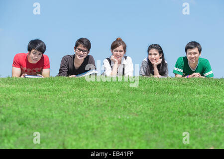 Gruppe von Studenten im Freien auf dem Boden liegend und lächelnd Stockfoto