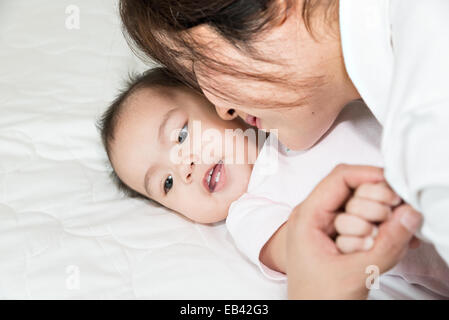Glückliche Familie fröhlich. Asiatische Mutter und Baby küssen, lachen und umarmen Stockfoto