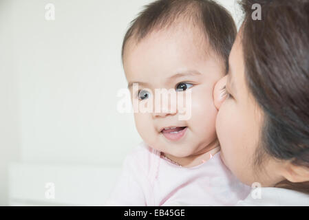 Glückliche Familie fröhlich. Asiatische Mutter und Baby küssen, lachen und umarmen Stockfoto