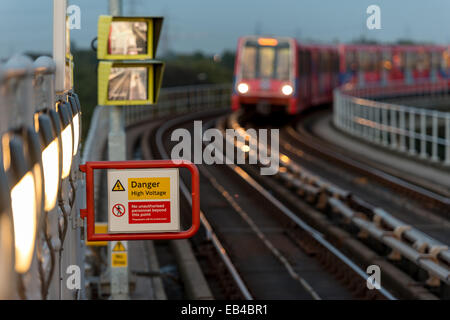 Strom-Warnung: Gefahr Hochspannung Zeichen auf Plattform und Docklands Light Railway in East London Stockfoto
