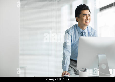 Junger Geschäftsmann mit Computer im Büro Stockfoto