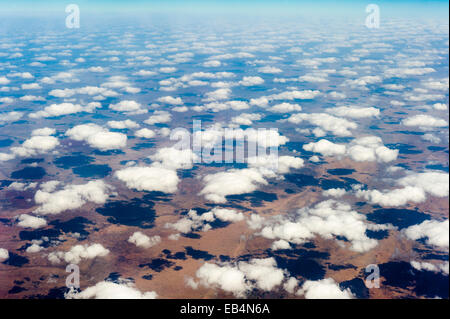 Eine Flottille von weißen flauschigen Wolken Schatten auf eine weite Wüstenebene. Stockfoto