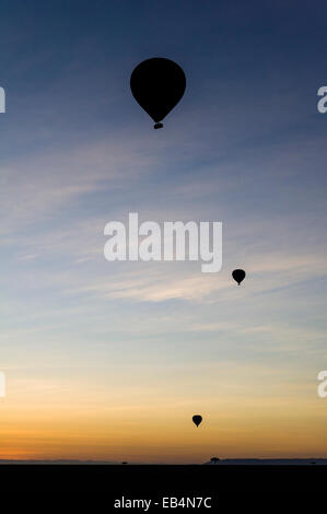 Die Silhouette des Heißluftballons steigen in den Himmel vor Sonnenaufgang über der dunklen afrikanischen Savanne-Ebene. Stockfoto