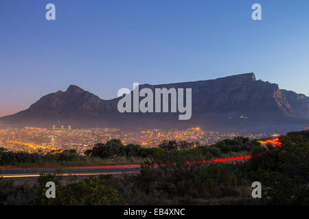 Tafelberg in der Dämmerung mit einem vorbeifahrenden Autos und Citylights Stockfoto