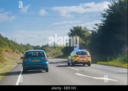 Ein Polizeiauto überholt Verkehr mit Notfall blau Blaulicht auf einer Uk-Straße Stockfoto