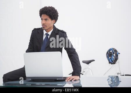 Nachdenklich Geschäftsmann im Trenchcoat mit laptop Stockfoto